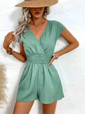 Textured wrap romper with smocked waist and short sleeves in a light green hue.