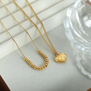 Gold layered necklaces with beaded chain and checkered heart charm