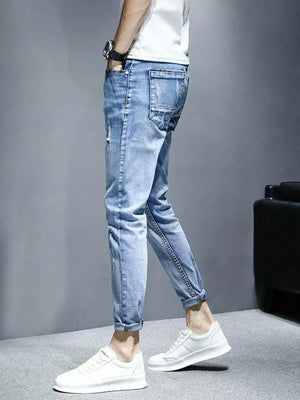 Light wash distressed slim fit jeans with rolled cuffs and whiskering detail.