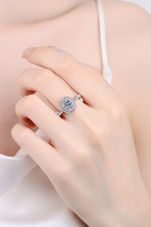 Silver ring with oval halo and pink stone accents on a hand.