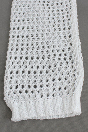 White crochet blouse with open knit pattern and ribbed hem detail.
