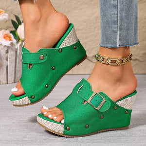 Green wedge sandals with decorative accents and buckle detail.