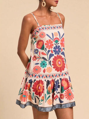 Playful printed mini dress with spaghetti straps and tiered skirt in multicolor floral pattern.