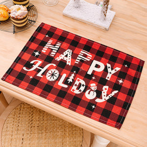 Red and black plaid placemat with white "Happy Holidays" text, snowman, and tree graphic.