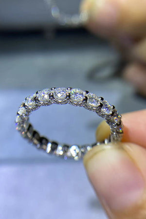 Silver eternity band ring with round moissanite stones.