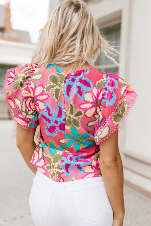 Floral ruffle sleeve silk blouse with pink trim and vibrant floral print.