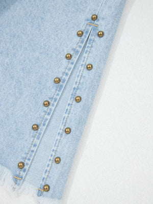 Light wash denim jeans with studded side slits and frayed hem detail.