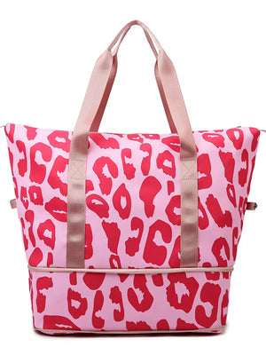 Vibrant leopard print travel bag with pink and red animal print and tan straps.