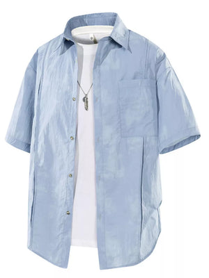 Men's blue short sleeve buttoned shirt with pocket detail over white undershirt.