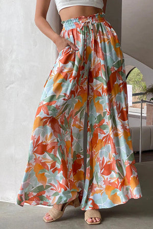 Botanical print palazzo trousers with a drawstring waist and wide legs in orange, aqua, and green.