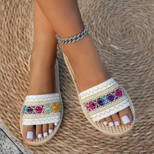 Embossed strap open-toe flat sandals with colorful embroidered detail and braided sole.