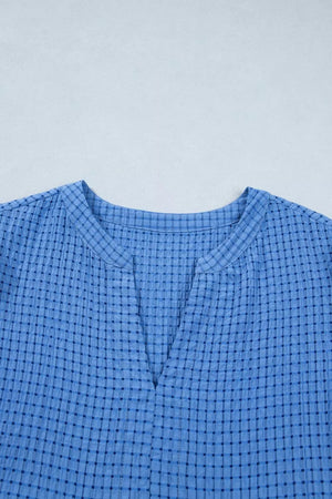 Blue checkered midi dress with notched neckline and textured fabric.