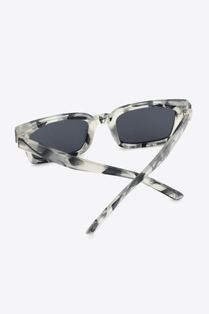 Marble effect rectangular sunglasses with dark lenses and clear frames.