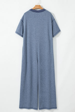 Denim-trimmed wide-leg utility jumpsuit in dusty blue with short sleeves and a collar.
