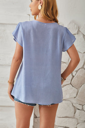 Light blue textured v-neck blouse with pleated flutter sleeves.