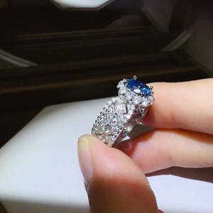 Silver ring with blue oval gemstone and diamond halo on textured band