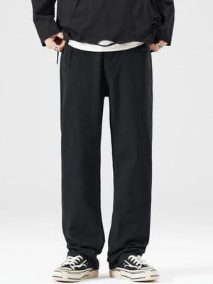 Men's black wide-leg jeans with a relaxed fit, styled with a white t-shirt and sneakers.