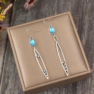 Silver dangle earrings with azure oval stones and elongated leaf-shaped drops.