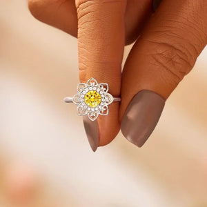 Silver ring with yellow center stone and white accent stones in a floral filigree design.