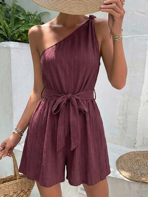 Chic one-shoulder romper in burgundy with tie waist and textured fabric.