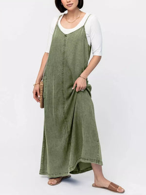 Moss denim maxi dress with V-neck and adjustable straps, styled with a white tee.
