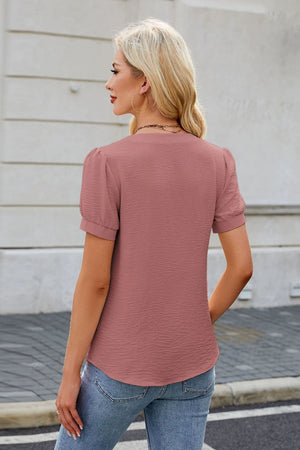 Dusty pink textured blouse with puff sleeves and bow-tie front detail.