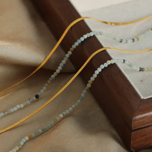 Gold layered necklace set with small light blue and tan beads and yellow ribbon detail