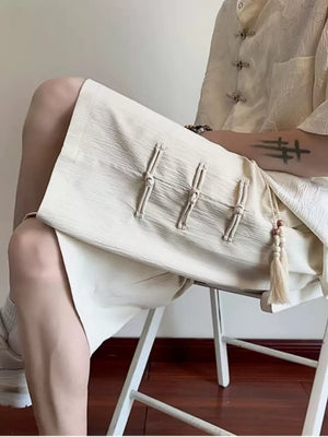 Beige chino shorts with drawstring and tassel detail, featuring decorative knot closures.