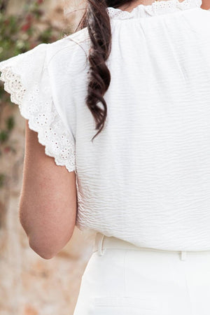 White textured blouse with eyelet trim flutter sleeves and ruffled neckline