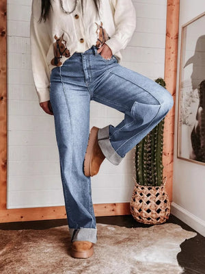 Light blue denim wide-leg jeans with buttoned pockets and cuffed hems.