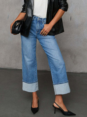 Light wash denim jeans with wide legs and large cuffs, styled with a black blazer.