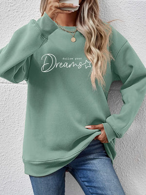 Sage oversized sweatshirt with white "Dreams follow your" graphic print and crew neckline.