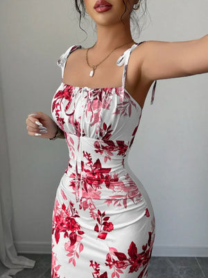 Floral print maxi dress in white with red and pink flowers, tie straps, and ruched bodice.