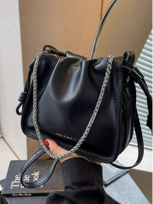 Black ruched PU leather crossbody bag with silver chain detail and knotted strap accents.