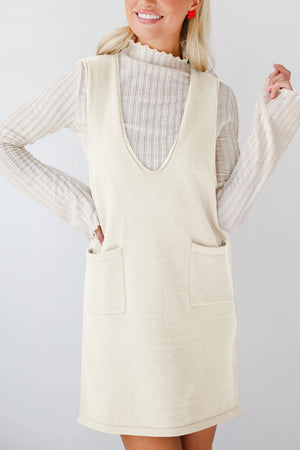 Cream sleeveless knit pocket dress with V-neck and ribbed mock neck top.