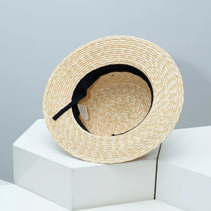 Elegant straw boater hat in tan with black ribbon trim, showing interior detail.