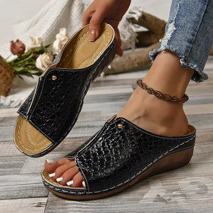 Black glossy crocodile-embossed wedge sandals with open toe and white stitching.
