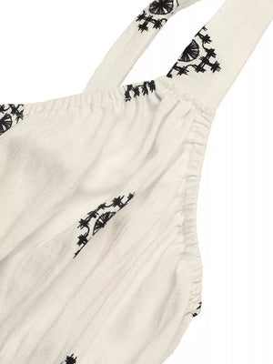 White midi dress with black geometric print, wide straps, and gathered detail.