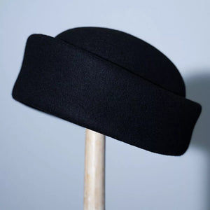Black wool pillbox hat with a folded brim detail.