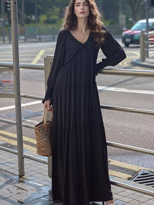 Black smocked v-neck tiered maxi dress with long sleeves and a basket bag.