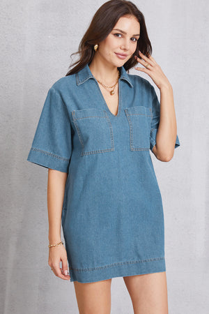 Denim mini dress in medium wash with plunging collar, short sleeves, and chest pockets.