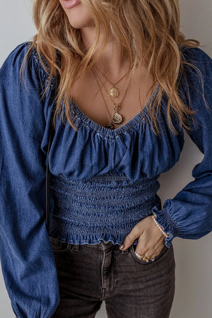 Denim corset blouse with smocked waist and blouson sleeves.