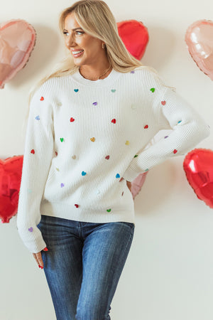 White ribbed knit sweater with colorful heart embellishments.