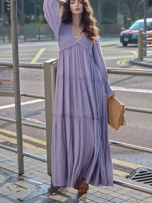 Purple smocked V-neck tiered maxi dress with long sleeves and a flowy skirt.
