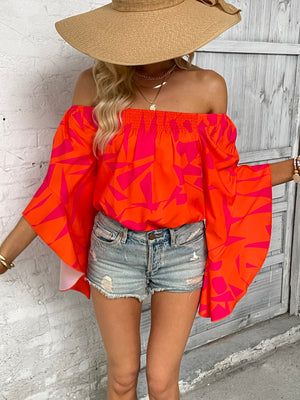 Orange geometric print off-shoulder blouse with flared bell sleeves.