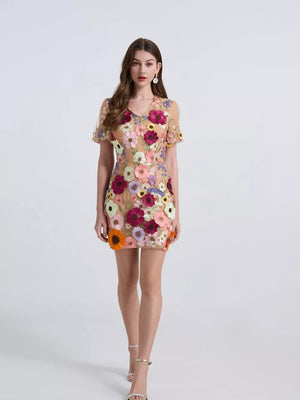 Embroidered floral mini dress with puff sleeves in a sheer nude fabric with colorful applique flowers.