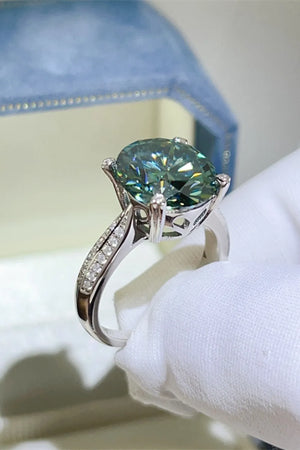 Dark green moissanite solitaire ring with diamond band detail on silver.