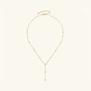 Gold lariat necklace with scattered moissanite stones and a drop pendant.