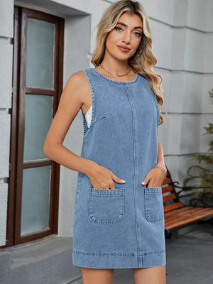 Sleeveless light blue denim pinafore dress with front patch pockets and seam detail.