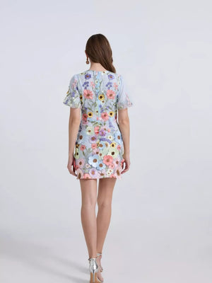 Embroidered floral mini dress in sky blue with puff sleeves and colorful applique flowers.
